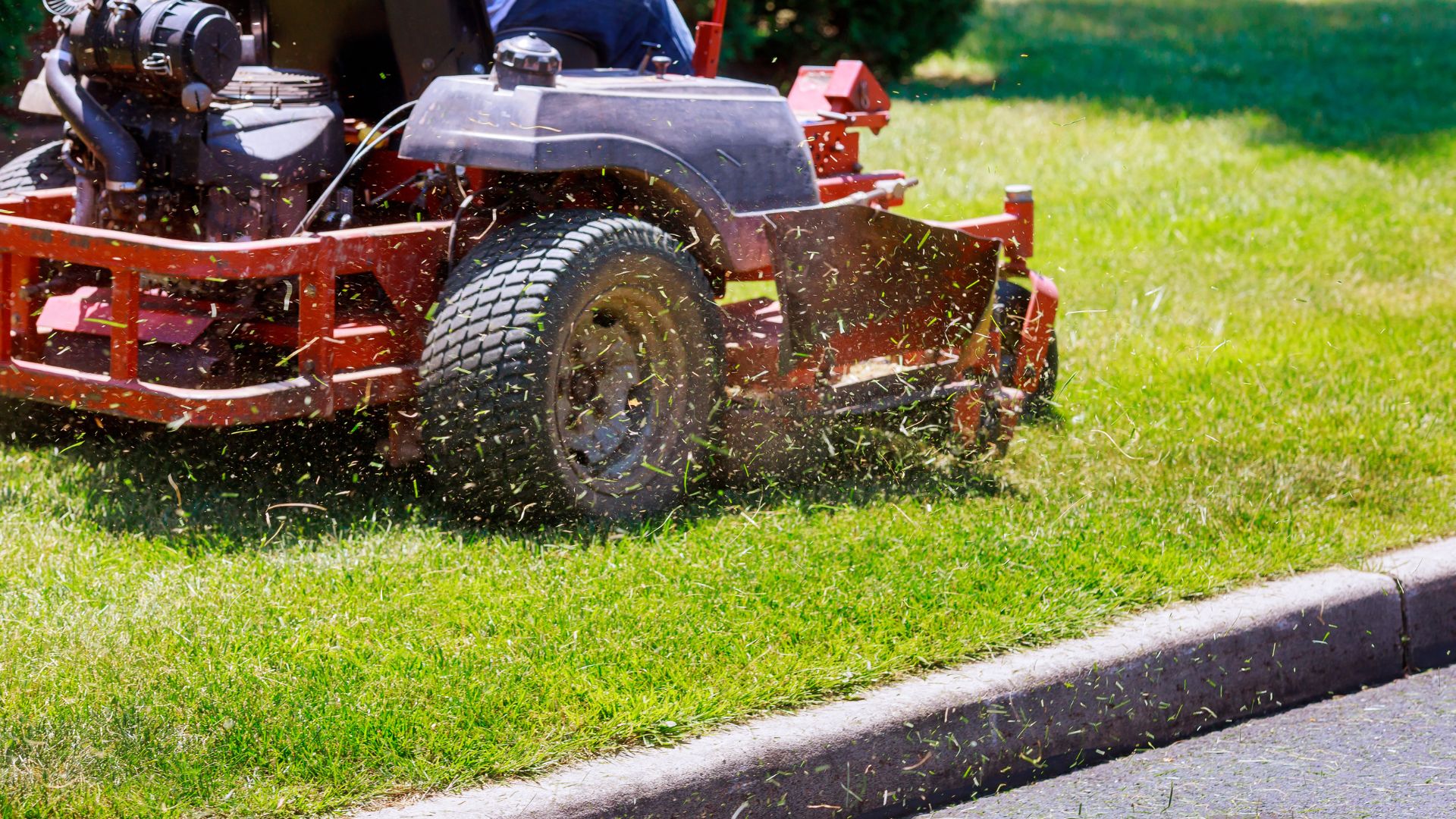 A man riding on the back of a red lawn mower