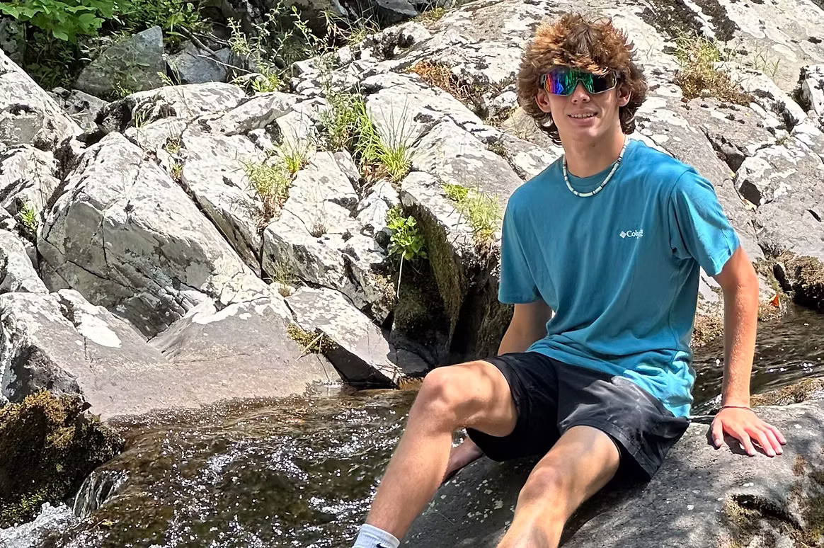 A man sitting on a rock next to a river